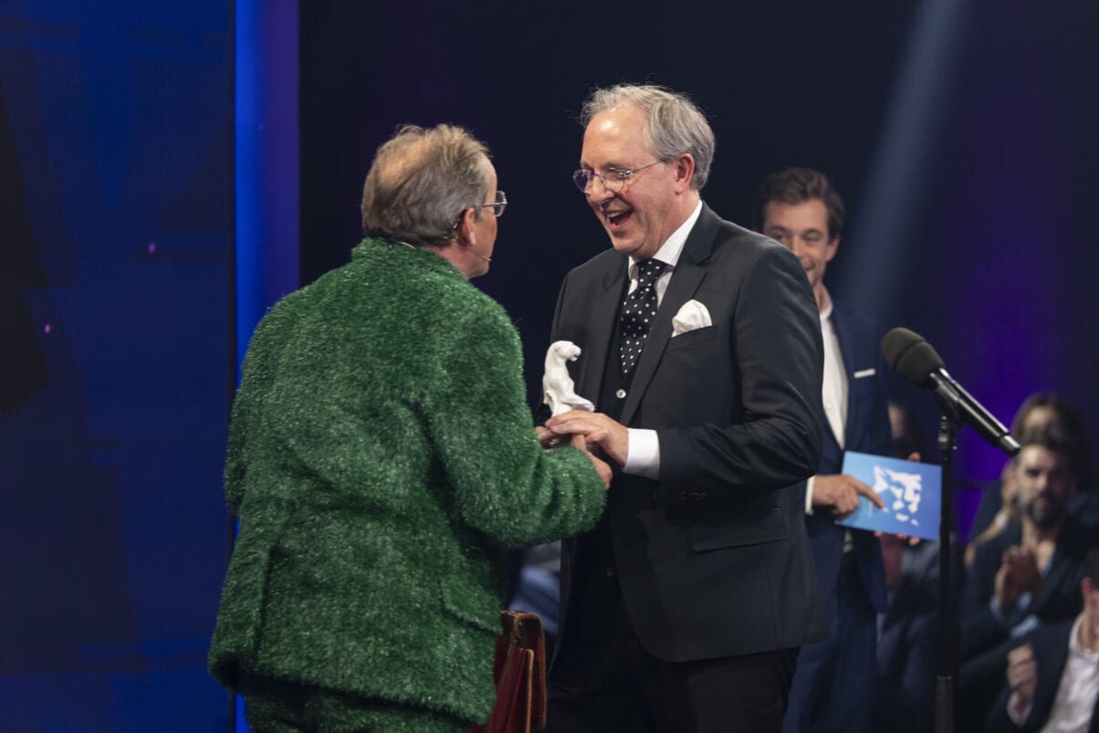 Two men in suits shaking hands at a awards ceremony