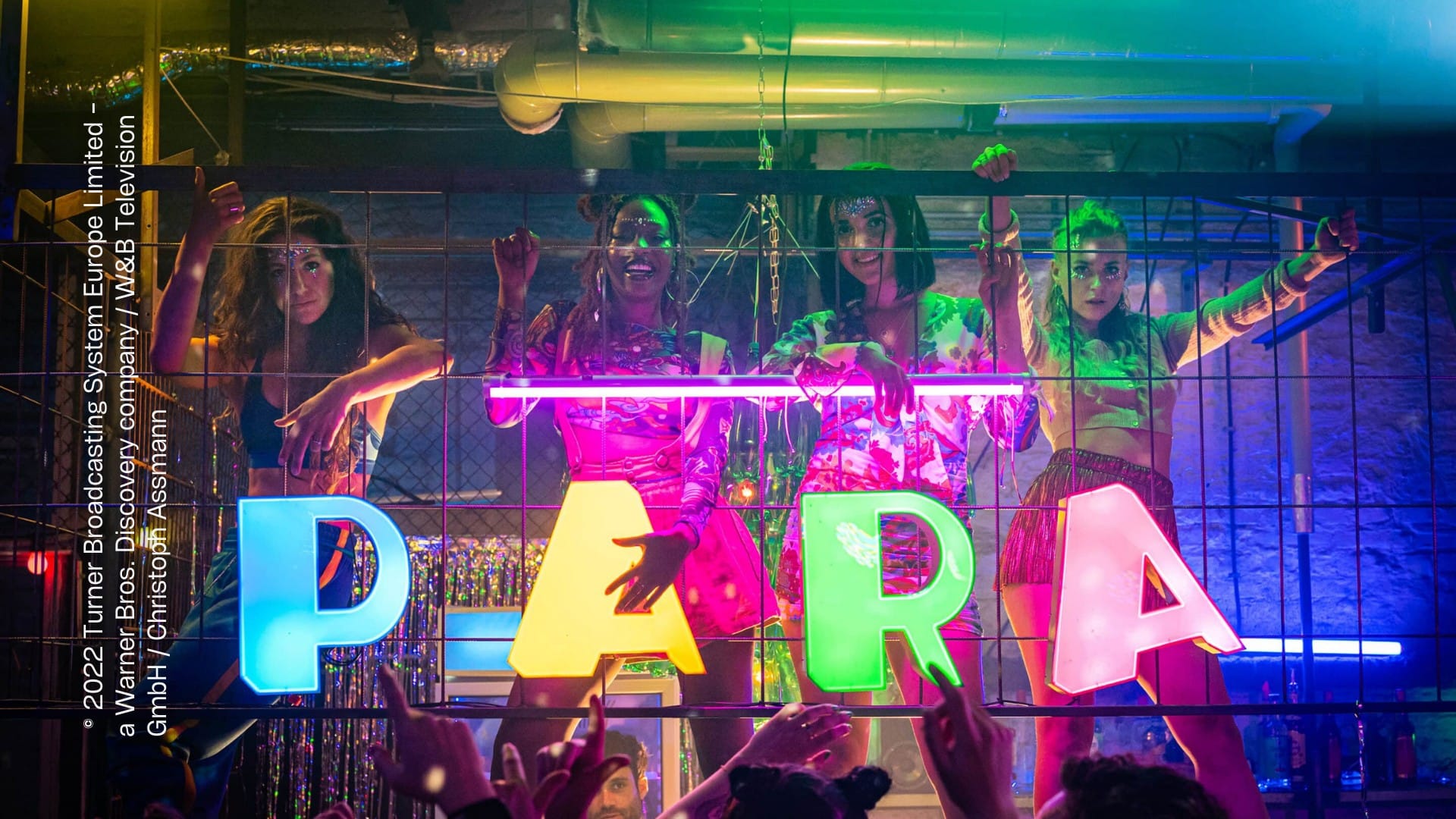 In einem Club stehen vier Frauen au feiner Erhöhung. Vor jeder Frau steht ein Leuchtbuchstabe - zusammen ergeben sie "PARA". Rundherum werden sie von einem Publikum bejubelt