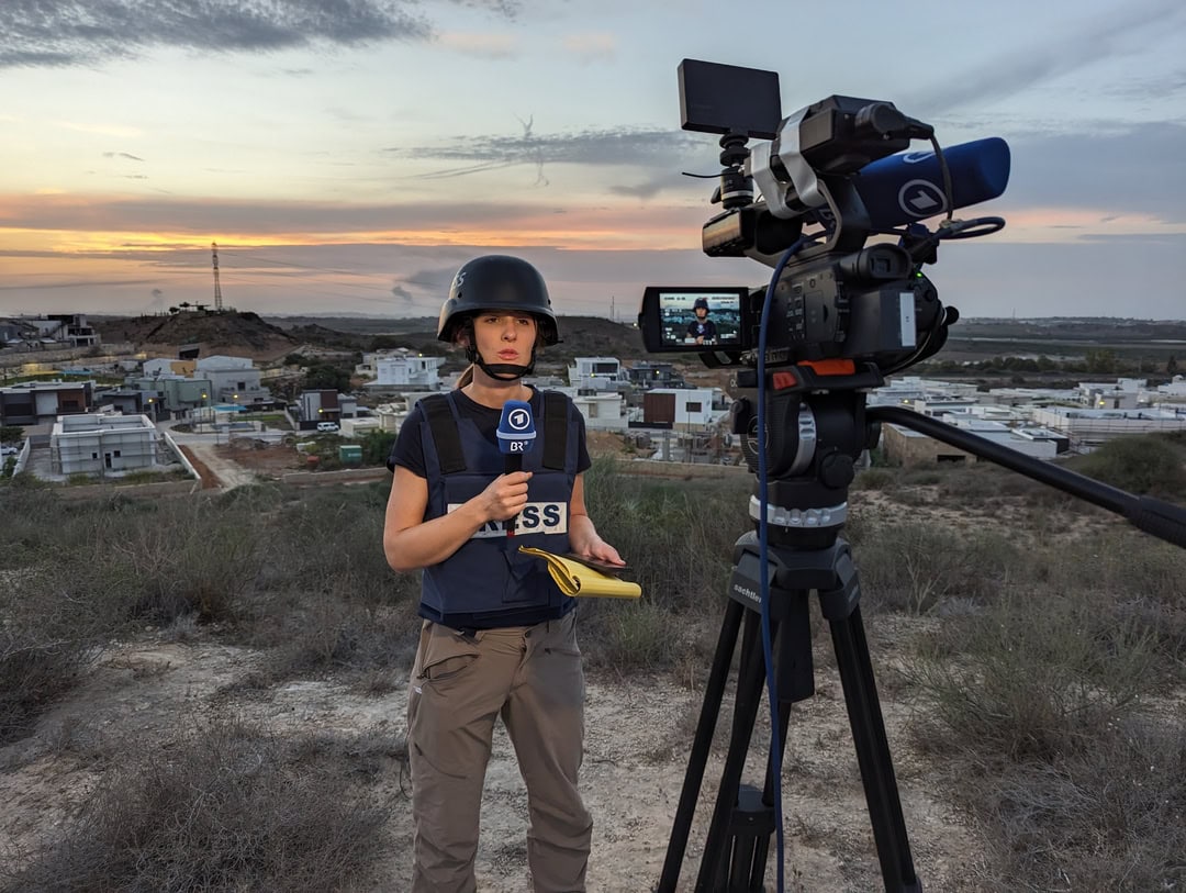 Sophie von der Tann, Korrespondentin im ARD-Studio Tel Aviv, berichtet live aus Sderot. Einen Kilometer entfernt im Hintergrund liegt die Grenze zum Gazastreifen. (c) ARD / BR