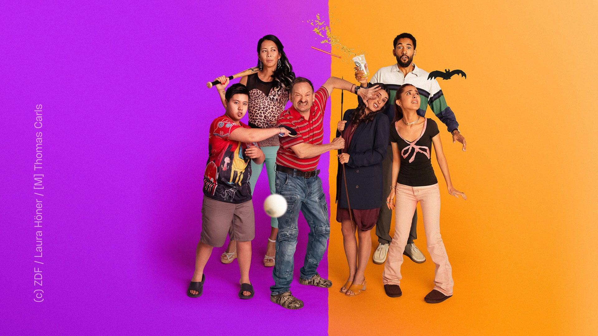 Zwei Familien stehen nebeneinander. Jede Familie besteht aus Mutter, Vater und Kind: Einmal mit einer Tochter, einmal mit einem Sohn. Die Familie auf der linken Seite steht vor einem lila Hintergrund, die andere vor einem Orangenen Hintergrund. Beide Familien scheinen gegeneinander zu kämpfen, ein paar der Personen schauen entsetzt oder verwirrt. Die Stimmung scheint angespannt, aber auch überzogen und dadurch auch humorvoll.