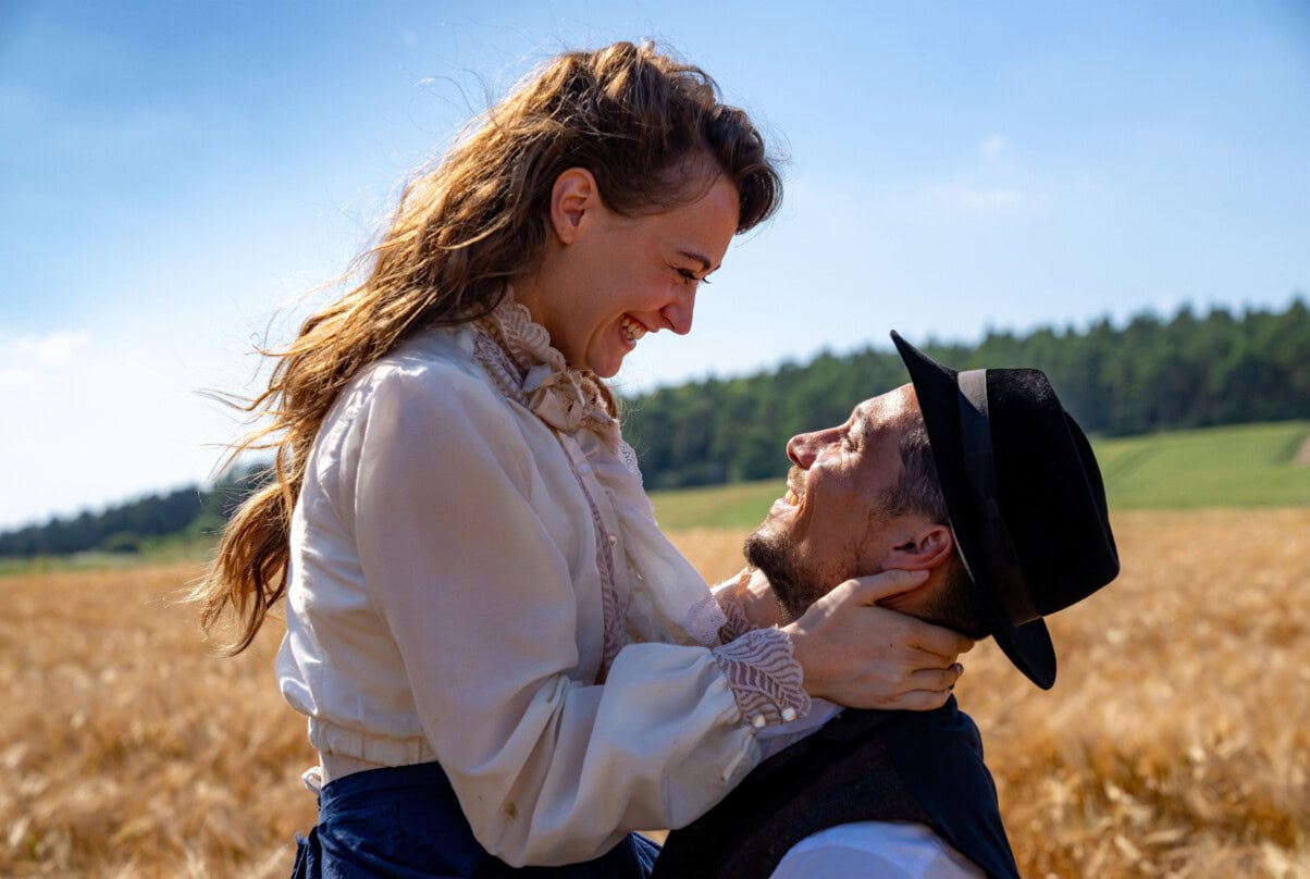 Liebespaar im Feld mit Sonnenbrille und Hut, romantisches Umarmung im Freien.