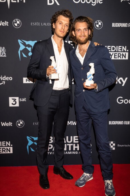 Benji und Jono Bergmann mit den Panther Statuen in der Hand vor der Pressewand 2022
