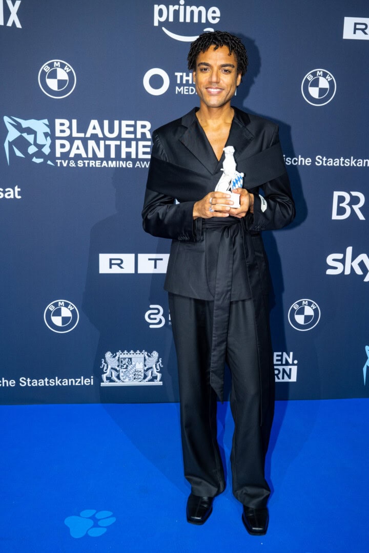 Lamin Leroy Gibba freut sich über den Blauen Panther 2025 in der Kategorie Fiktion als Hauptdarsteller, Creator, Ko-Produzent und Headautor von „Schwarze Früchte“ (Jünglinge Film & Studio Zentral / ARD Degeto Film für die ARD).