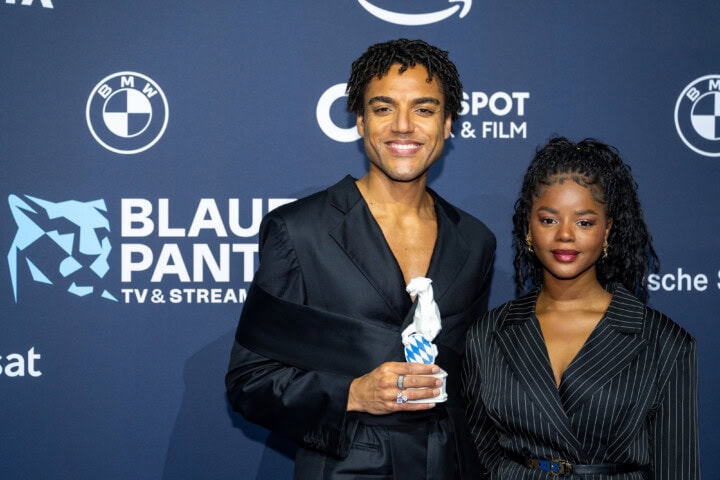 Lamin Leroy Gibba (l.) erhielt den Blauen Panther 2025 in der Kategorie Fiktion als Hauptdarsteller, Creator, Ko-Produzent und Headautor von „Schwarze Früchte“ (Jünglinge Film & Studio Zentral / ARD Degeto Film für die ARD) aus den Händen von Schauspielerin Melodie Simina (r.).