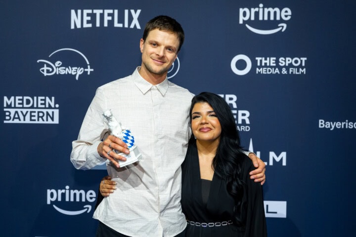 David Seeberg (l.) gewinnt den Blauen Panther 2025 in der Kategorie Kultur / Bildung als Autor, Regisseur und Kameramann der Dokumentation „BLOCK PARTY - Peter Fox feiert mit Berlin“ (Florida Factual im Auftrag von SWR, rbb, ARD Kultur und hr für die ARD). Den Preis überreichte Nachwuchssängerin und Protagonistin Cerin (r.).